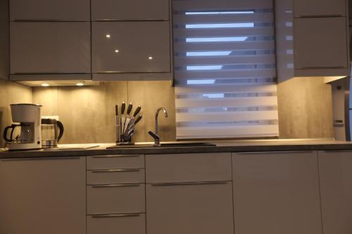 a kitchen with white cabinets and a sink at Sosnowe Domki in Rewal