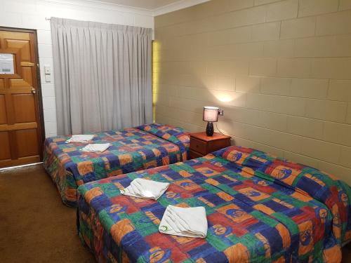 a hotel room with two beds and a lamp at Commercial Hotel in Charters Towers