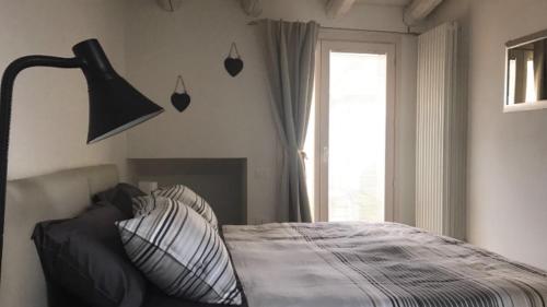 een slaapkamer met een bed met een lamp en een raam bij Antonella Gardalake 2 in Desenzano del Garda
