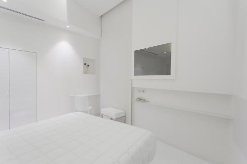 a white bedroom with a bed and a mirror at Vittorio Veneto Matera Luxury Rooms in Matera