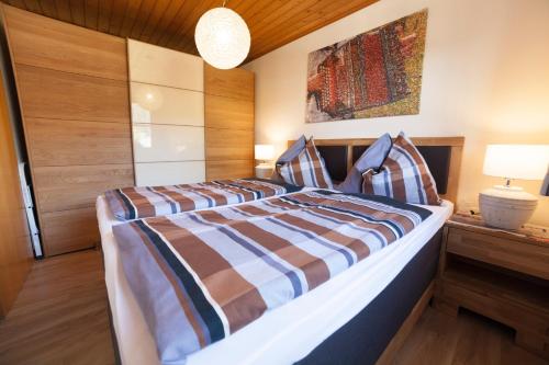 Schlafzimmer mit einem Bett mit gestreifter Decke in der Unterkunft Appartement Philips in Flachau
