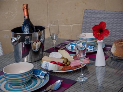 a table with a bottle of wine and plates and wine glasses at Seaview Luxury Penthouse with Shared Swimming Pool in Għajnsielem