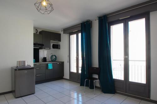 Il comprend une cuisine avec des rideaux bleus et une table. dans l'établissement Castellane - 40 m2 avec balcon et parking, à Toulouse