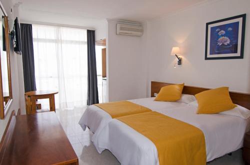 a hotel room with a large bed with yellow sheets at Aparthotel Vibra Bay in San Antonio