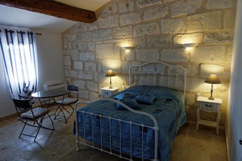 - une chambre avec un lit et un mur en pierre dans l'établissement Le Mas d'Isnard, à Arles