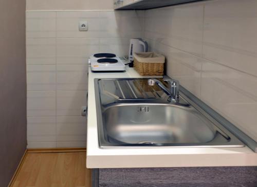 uma pequena cozinha com um lavatório e um fogão em Apartment Millas em Niš