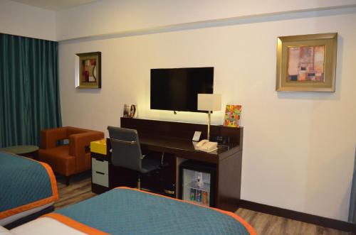 a hotel room with a bed and a desk with a television at Zone By The Park, ORR, Chennai in Chennai