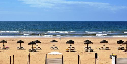 a beach with chairs and umbrellas and the ocean at Manta Rota Holiday Home in Manta Rota