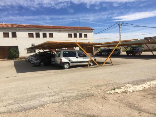 a carport with awning and cars parked in a parking lot at Hotel Restaurante Santa Cruz in Santa Cruz de Mudela