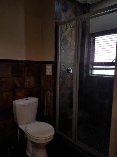 a bathroom with a toilet and a glass shower at Santai guesthouse in Brits