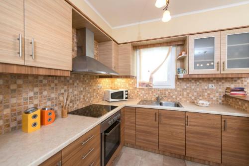 a kitchen with wooden cabinets and a microwave at Lorenzo Villas with Private Pool, 200m from the beach, by ZanteWize in Lithakia