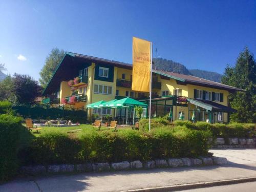 ein großes gelbes Gebäude mit einer Flagge davor in der Unterkunft Hotel-Restaurant Bellevue in Ruhpolding