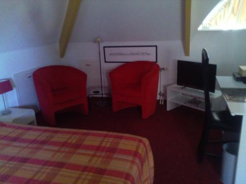 a room with two red chairs and a bed and a television at Bed & Breakfast aan Zee in Callantsoog