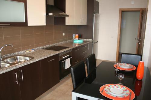 a small kitchen with a sink and a table with chairs at Edifice Ibérico in Albufeira