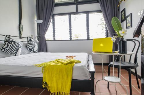 a bedroom with a bed with a yellow blanket on it at The Marian Boutique Lodging House in Kuching