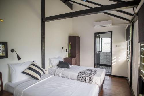 two beds in a room with white walls at The Marian Boutique Lodging House in Kuching