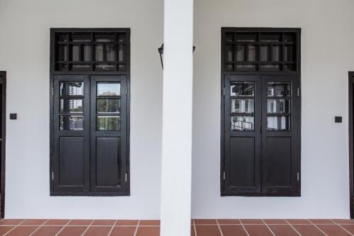 two black doors on a white wall at The Marian Boutique Lodging House in Kuching
