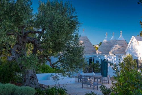 a house with a tree and a table and chairs at Tenuta del Lauro in Locorotondo