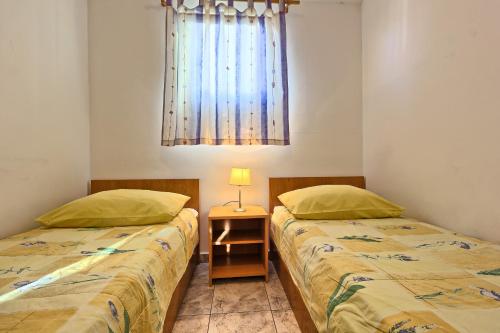 two twin beds in a room with a window at Apartments & Bungalows Ivanović in Kaštela