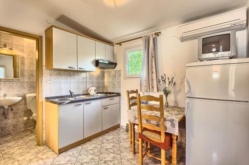 a kitchen with a refrigerator and a table with chairs at Apartments & Bungalows Ivanović in Kaštela