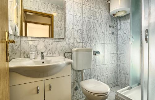 a bathroom with a sink and a toilet and a mirror at Apartments & Bungalows Ivanović in Kaštela