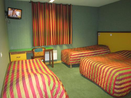 
a hotel room with two beds and a television at Hotel Siatel Metz in Norroy-le-Veneur
