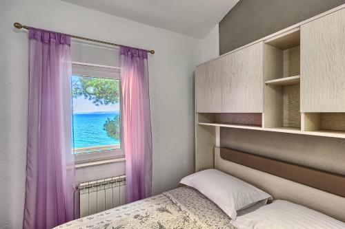 a bedroom with a bed and a window with purple curtains at Apartments & Bungalows Ivanović in Kaštela