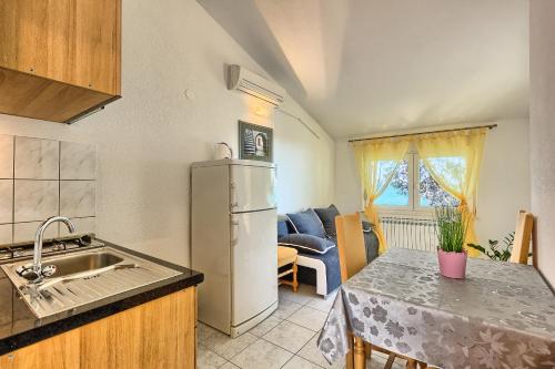 a kitchen with a sink and a refrigerator and a table at Apartments & Bungalows Ivanović in Kaštela