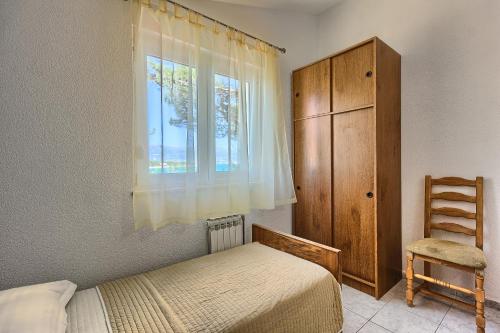 a bedroom with a bed and a window and a chair at Apartments & Bungalows Ivanović in Kaštela