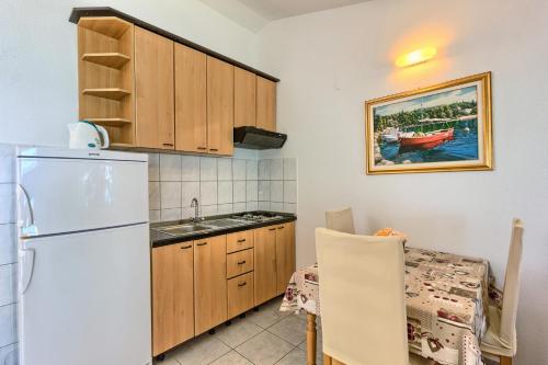 a kitchen with a white refrigerator and a table at Apartments & Bungalows Ivanović in Kaštela