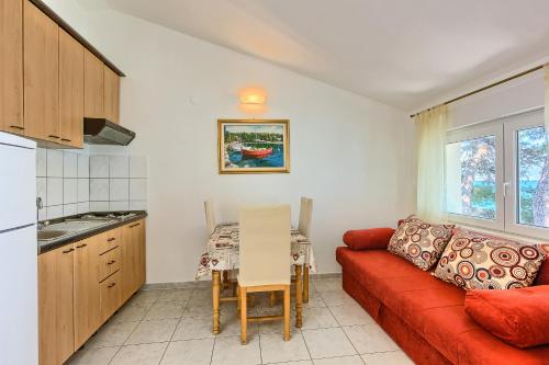 a living room with a red couch and a table at Apartments & Bungalows Ivanović in Kaštela