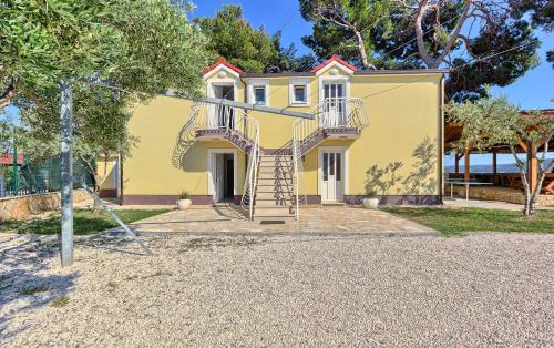 a yellow house with a spiral staircase in front of it at Apartments & Bungalows Ivanović in Kaštela