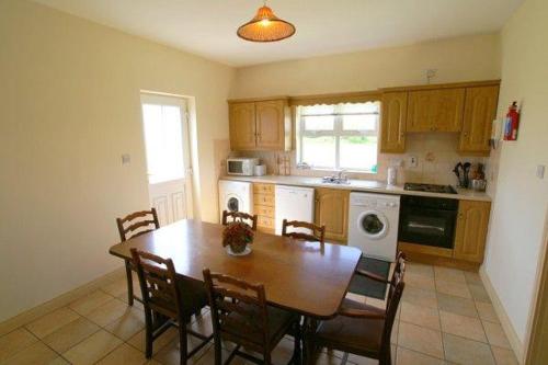a kitchen with a wooden table and chairs and a table and a kitchen with at Fairgreen Cottages in Dungloe
