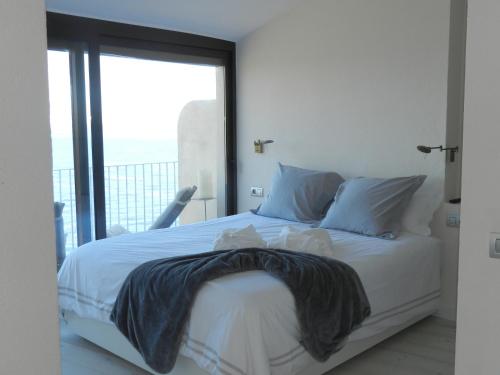 a bedroom with a white bed with a large window at Cap sa Sal Lofts in Begur