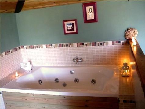a bath tub in a bathroom with two pictures on the wall at Posada Molino La Vega in Reinosilla