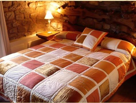 Cama grande en habitación con pared de piedra en Posada Molino La Vega en Reinosilla