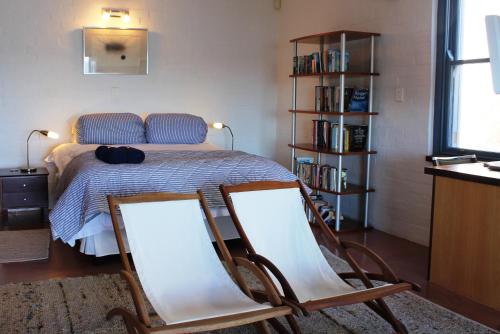 two chairs in front of a bed in a room at Seehuis Suite Bella in Langebaan