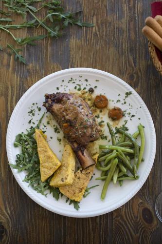 a plate of food with meat and vegetables on a table at Alma Living Hotel- Al Girarrosto in Venzone