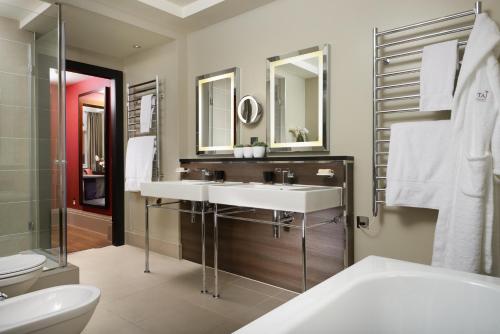 a bathroom with a sink and a toilet and a mirror at Taj 51 Buckingham Gate Suites and Residences in London