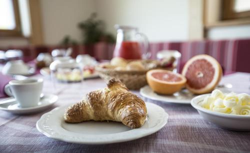 a table with plates of pastries and bowls of fruit at Alma Living Hotel- Al Girarrosto in Venzone