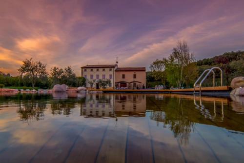 a large pond with a building and a water fountain at Agriturismo Casa Aurora in Bussolengo