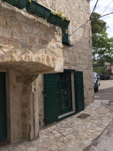 a stone building with a green door on it at room Ami in Kaštela