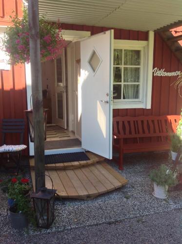 a front door of a red house with a porch at Gånarps rum och Stuguthyrning in Ängelholm