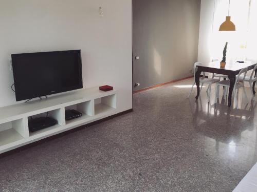 a living room with a television and a dining room table at Sunny family apartment in villa - HUMANITAS FORUM IEO in Pieve Emanuele