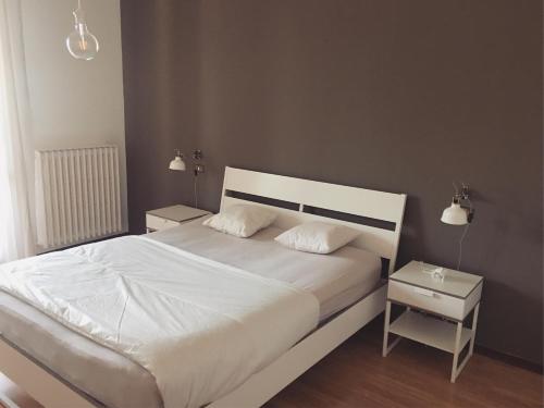 a bedroom with a white bed with two night stands at Sunny family apartment in villa - HUMANITAS FORUM IEO in Pieve Emanuele