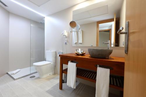 een badkamer met een wastafel, een toilet en een spiegel bij Sandos El Greco - Adults Only in Portinatx