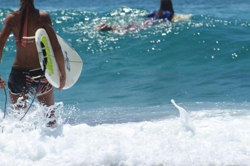a man walking into the ocean with a surfboard at Sentidos Beach Retreat in Miramar