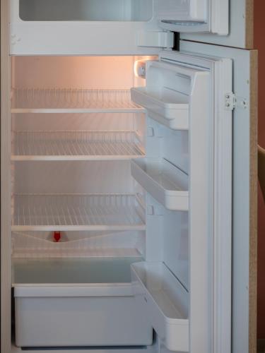 an empty refrigerator with its door open and a red object in it at Seaview Luxury Penthouse with Shared Swimming Pool in Għajnsielem