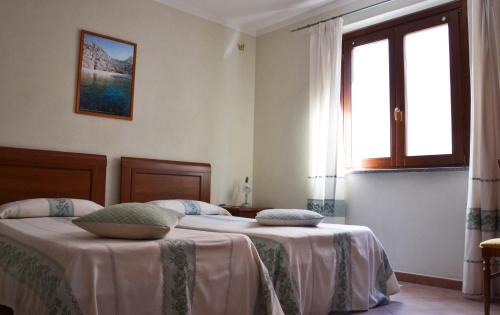 a bedroom with two beds and a window at Hotel da Paolino in Trinità dʼAgultu