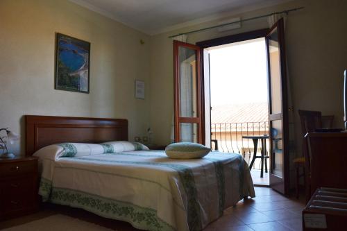 a bedroom with a bed and a large window at Hotel da Paolino in Trinità d'Agultu e Vignola